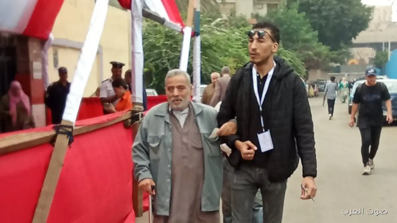 شاب يساعد مسن في مدرسة أبو الهول بالجيزة عشان يدلي بصوته في الانتخابات